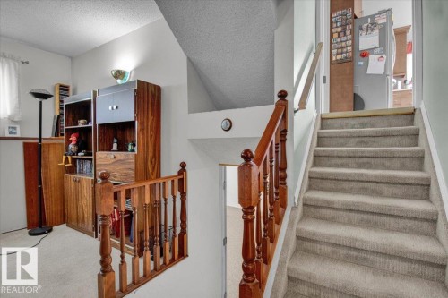 This interior view features a carpeted staircase with a wooden banister and handrail, alongside a landing area - 3523 18A Avenue, Edmonton, AB - Indoor Photo Showing Other Room
