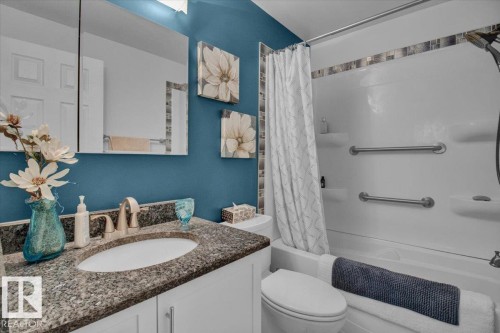 Bathroom featuring a vanity with a granite countertop, an integrated sink, a built-in mirror, and a shower-tub combination with a shower curtain - 3523 18A Avenue, Edmonton, AB - Indoor Photo Showing Bathroom