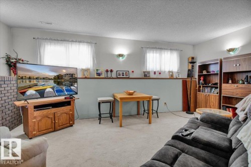 Spacious room featuring light-colored carpeting, two windows with white sheer curtains, and integrated wall lighting - 3523 18A Avenue, Edmonton, AB - Indoor Photo Showing Living Room