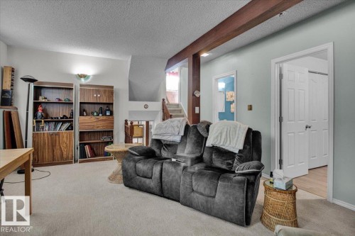This versatile living area features carpeted flooring and light blue walls, providing a bright and inviting atmosphere - 3523 18A Avenue, Edmonton, AB - Indoor Photo Showing Living Room