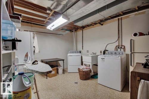 The property features a dedicated utility space with white walls, exposed ceiling joists, and a speckled floor - 3523 18A Avenue, Edmonton, AB - Indoor Photo Showing Laundry Room