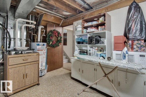 The property features exposed ceiling joists and ductwork, a water heater, and built-in shelving units for storage - 3523 18A Avenue, Edmonton, AB - Indoor