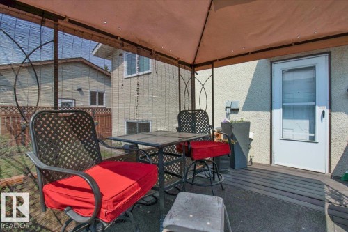The property features a covered patio area with a privacy screen and a door leading into the home - 3523 18A Avenue, Edmonton, AB - Outdoor With Deck Patio Veranda With Exterior