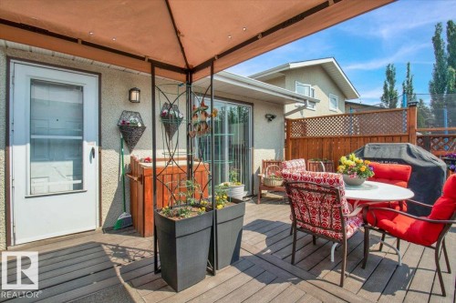 The property features a wood deck with a privacy fence and a white patio dining set with red cushions - 3523 18A Avenue, Edmonton, AB - Outdoor With Deck Patio Veranda With Exterior