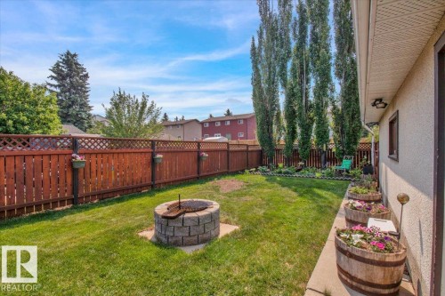 The property features a fenced yard with a stone fire pit and a lawn area - 3523 18A Avenue, Edmonton, AB - Outdoor