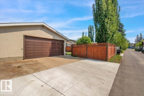 This property features an attached garage with a brown panelled door and a concrete driveway - 3523 18A Avenue, Edmonton, AB - Outdoor