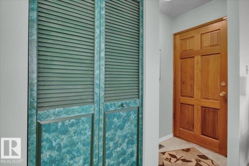 The entryway features a paneled wooden door and a closet with louvered bifold doors - 3523 18A Avenue, Edmonton, AB - 