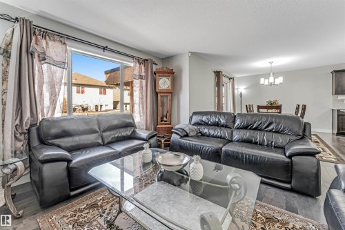 Living area featuring dark hardwood floors, a large window with drapes, and an open layout that leads to the dining area - 2244 21 Avenue, Edmonton, AB - Indoor Photo Showing Living Room