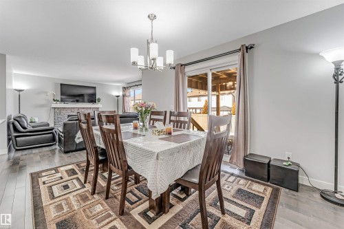 The dining area features hard flooring, a decorative area rug, and a modern chandelier - 2244 21 Avenue, Edmonton, AB - Indoor Photo Showing Dining Room