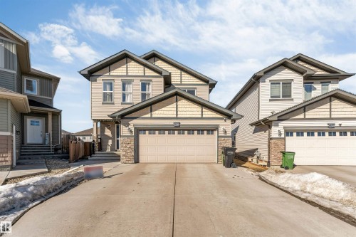 The property features a two-story exterior with a two-car garage, light-colored siding, and stone accents - 2244 21 Avenue, Edmonton, AB - Outdoor With Facade