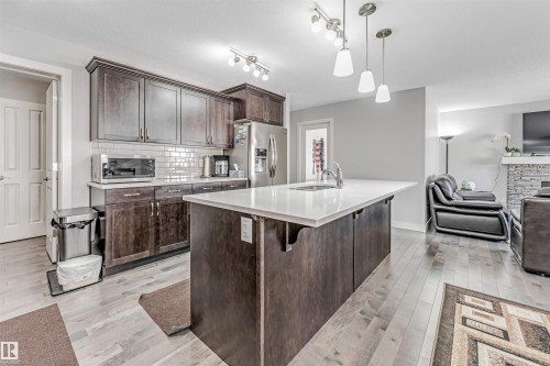 The kitchen features dark wood cabinetry, a white subway tile backsplash, and a large island with a white countertop and sink - 2244 21 Avenue, Edmonton, AB - Indoor Photo Showing Kitchen With Upgraded Kitchen