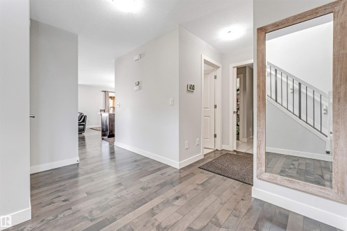 The entry hallway features light-toned hardwood flooring, white baseboards, and a contemporary staircase with metal railings - 2244 21 Avenue, Edmonton, AB - Indoor Photo Showing Other Room