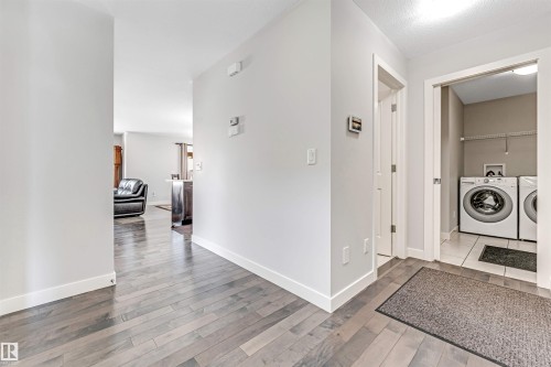 The property features a laundry area with a washer and dryer, tiled flooring, and a storage shelf - 2244 21 Avenue, Edmonton, AB - Indoor