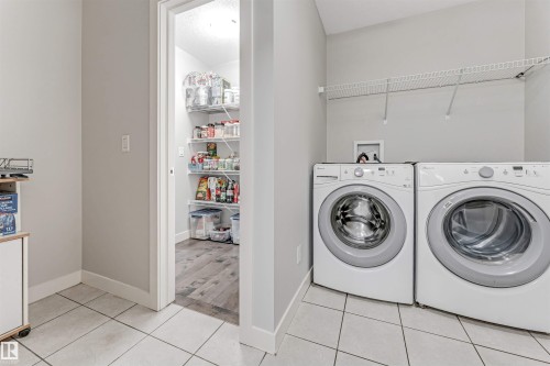 The property includes a dedicated laundry area with tile flooring and a wire shelf, alongside a pantry featuring wire shelving and wood-look flooring - 2244 21 Avenue, Edmonton, AB - Indoor Photo Showing Laundry Room