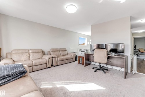 The property features a spacious room with light-colored carpeted flooring, light-toned walls, and a window providing natural light - 2244 21 Avenue, Edmonton, AB - Indoor