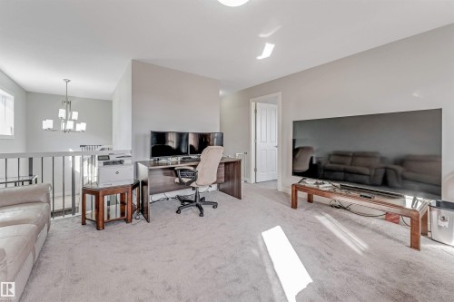 The property features a bright loft area with light gray carpet, a spacious wall, and a staircase with a white railing and dark balusters - 2244 21 Avenue, Edmonton, AB - Indoor Photo Showing Living Room