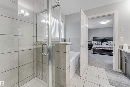 Bathroom featuring a glass-enclosed shower, a built-in bathtub, and a vanity with a white countertop and dark cabinetry - 2244 21 Avenue, Edmonton, AB - Indoor Photo Showing Bathroom
