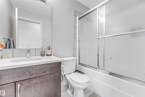 Bathroom featuring a vanity with a white countertop and dark wood cabinetry, a mirror, and a shower with frosted sliding doors - 2244 21 Avenue, Edmonton, AB - Indoor Photo Showing Bathroom