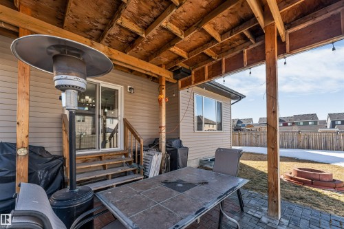 The property features a covered patio area with exposed wood beams, string lighting, and a paved surface - 2244 21 Avenue, Edmonton, AB - Outdoor With Deck Patio Veranda With Exterior