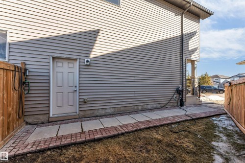 The property features light-colored horizontal siding, a wooden fence, and a paved walkway with brick edging - 2244 21 Avenue, Edmonton, AB - Outdoor With Exterior