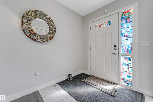 The property features a white entry door with decorative glass inserts and a sidelight with colorful patterned glass - 2244 21 Avenue, Edmonton, AB - Indoor Photo Showing Other Room