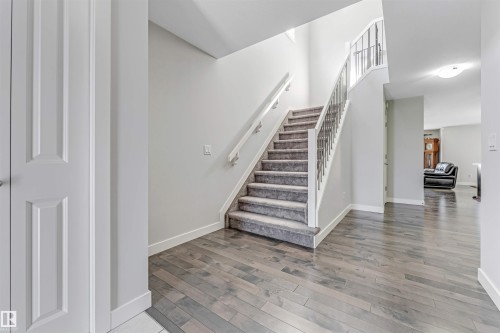 The entryway features wood flooring and a carpeted staircase with a metal railing - 2244 21 Avenue, Edmonton, AB - Indoor Photo Showing Other Room