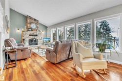 Living room featuring hardwood floors, a stone fireplace, and a vaulted ceiling - 