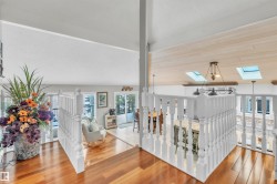 The property features hardwood floors and white railings, with a vaulted ceiling and skylights providing natural light - 