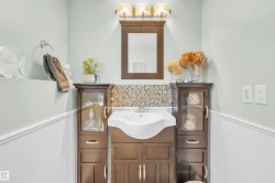 The bathroom features a vanity with a white sink, a mosaic tile backsplash, and a mirror with a light fixture above it - 