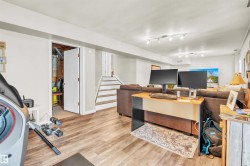 This versatile lower level features durable wood-look flooring, recessed lighting, and a white staircase leading to the upper level - 