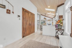 The property features a vaulted ceiling with light wood paneling and skylights, complemented by light-colored floor tiles - 