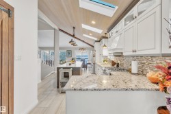 The kitchen features white cabinetry, stone countertops, a tile backsplash, and a gas range - 