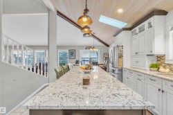 The kitchen features white cabinetry, granite countertops, a tiled backsplash, and stainless steel appliances - 