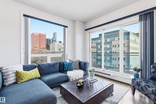 The living area features large windows offering city views and a sliding glass door providing access to a balcony - 601 10504 99 Avenue, Edmonton, AB - Indoor Photo Showing Living Room