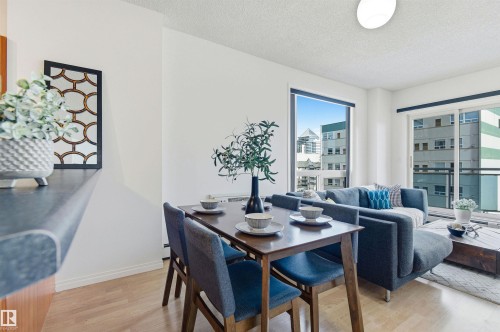 This bright living space features light-toned flooring, white walls, and large windows offering urban views - 601 10504 99 Avenue, Edmonton, AB - Indoor Photo Showing Dining Room