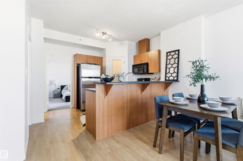 The kitchen features wood cabinetry, stainless steel appliances, and a breakfast bar - 601 10504 99 Avenue, Edmonton, AB - Indoor