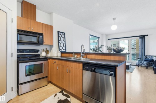 The kitchen features stainless steel appliances, wood cabinetry, and a double basin sink - 601 10504 99 Avenue, Edmonton, AB - Indoor Photo Showing Kitchen With Double Sink