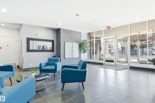 Inviting lobby area featuring tiled flooring, comfortable blue armchairs, and a decorative mirror - 601 10504 99 Avenue, Edmonton, AB - Indoor