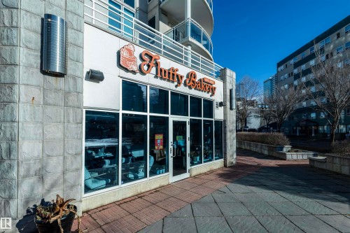 The property features a storefront with large windows, a glass entrance door, and exterior lighting fixtures - 601 10504 99 Avenue, Edmonton, AB - Outdoor
