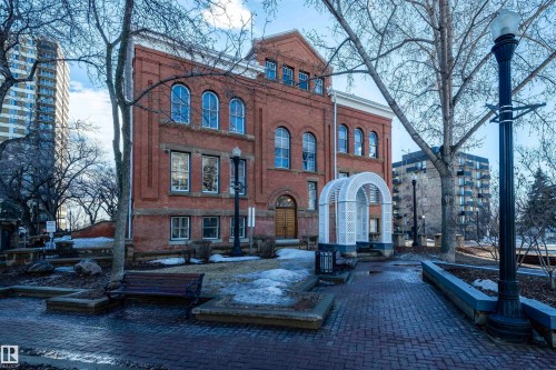 The property features a red brick exterior with arched windows, a front entrance with wooden doors, and a decorative white archway - 601 10504 99 Avenue, Edmonton, AB - Outdoor With Facade