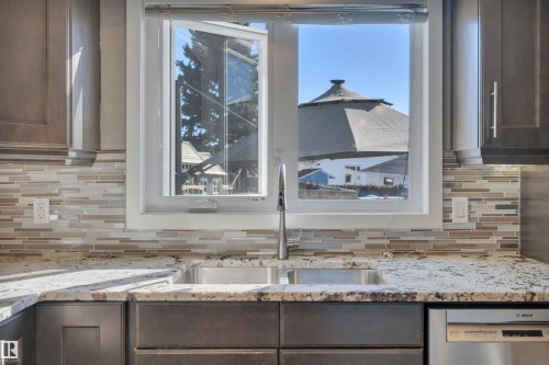 The kitchen features a stainless steel sink, a modern faucet, and light-colored granite countertops - 8807 31 Avenue, Edmonton, AB - Indoor Photo Showing Kitchen With Double Sink With Upgraded Kitchen