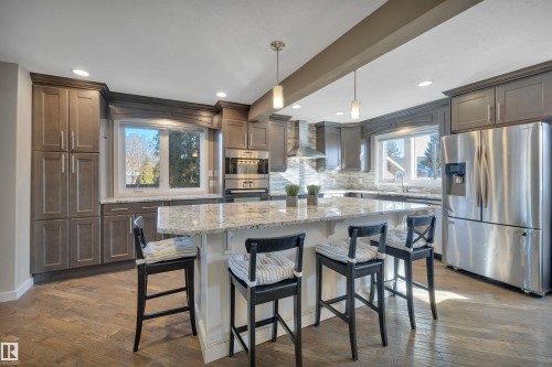 The kitchen features an island with a light-colored countertop, recessed lighting, pendant lights, and stainless steel appliances - 8807 31 Avenue, Edmonton, AB - Indoor Photo Showing Kitchen With Upgraded Kitchen