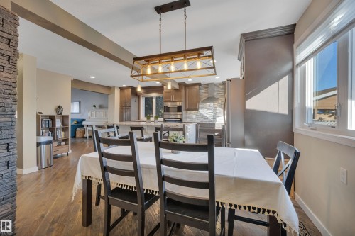 Dining area featuring hardwood floors, a prominent window, and a decorative light fixture - 8807 31 Avenue, Edmonton, AB - Indoor Photo Showing Dining Room