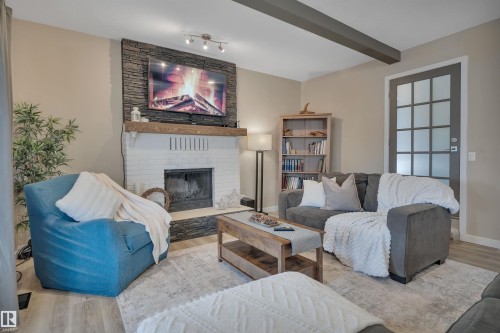 Living room featuring a fireplace with a white brick base, a natural stone surround, and a wooden mantel - 8807 31 Avenue, Edmonton, AB - Indoor Photo Showing Living Room With Fireplace