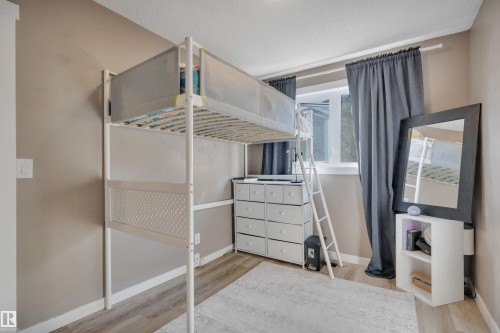 This room features neutral-toned walls, wood-style flooring, and a window with dark curtains - 8807 31 Avenue, Edmonton, AB - Indoor