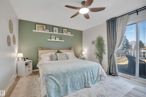 This room features light-toned flooring, a ceiling fan with integrated lighting, and a sliding glass door providing access to the outdoors - 8807 31 Avenue, Edmonton, AB - Indoor Photo Showing Bedroom
