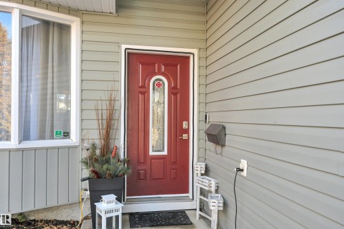 The property features a bold red entry door with decorative glass, complemented by light grey horizontal siding - 8807 31 Avenue, Edmonton, AB - Outdoor With Exterior