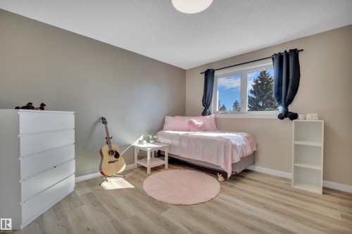 Bedroom featuring light-toned flooring, a window providing natural light, and neutral colored walls - 8807 31 Avenue, Edmonton, AB - Indoor Photo Showing Bedroom