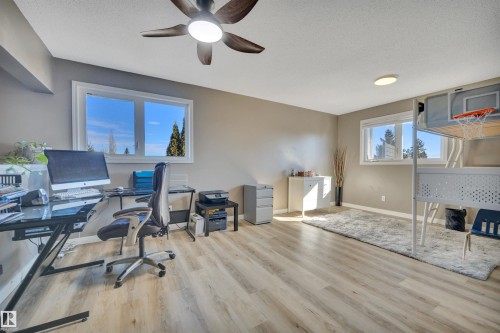 This versatile room features light-toned flooring, two windows providing natural light, and a ceiling fan with integrated lighting - 8807 31 Avenue, Edmonton, AB - Indoor Photo Showing Office