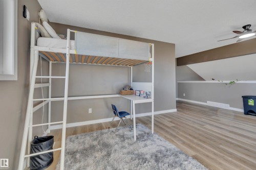 This room features light wood-style flooring, a sloped ceiling, and a ceiling fan - 8807 31 Avenue, Edmonton, AB - Indoor